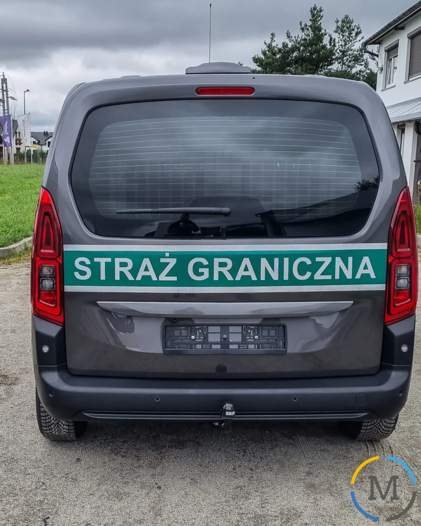 Tył ciemnoszarego radiowozu polskiej Straży Granicznej z zielonym pasem odblaskowym i napisem Straż Graniczna