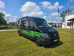 Czarno-zielony furgon serwisowy Volkswagen Crafter firmy WOT-EL elektrotechnika zaparkowany na trawniku